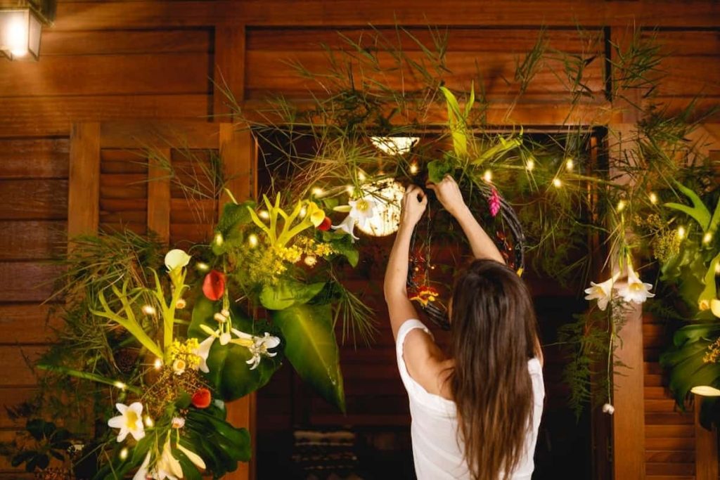 Woman attaching garland Christmas lights on the door