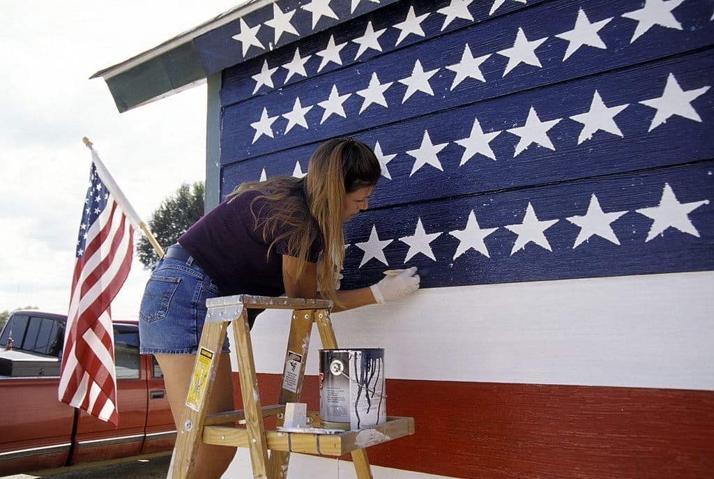a woman is painting her house an american flag