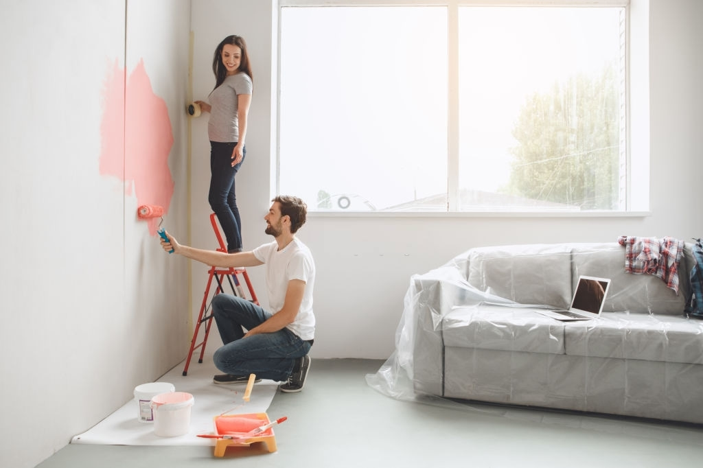a couple is painting their wall pink in a room together