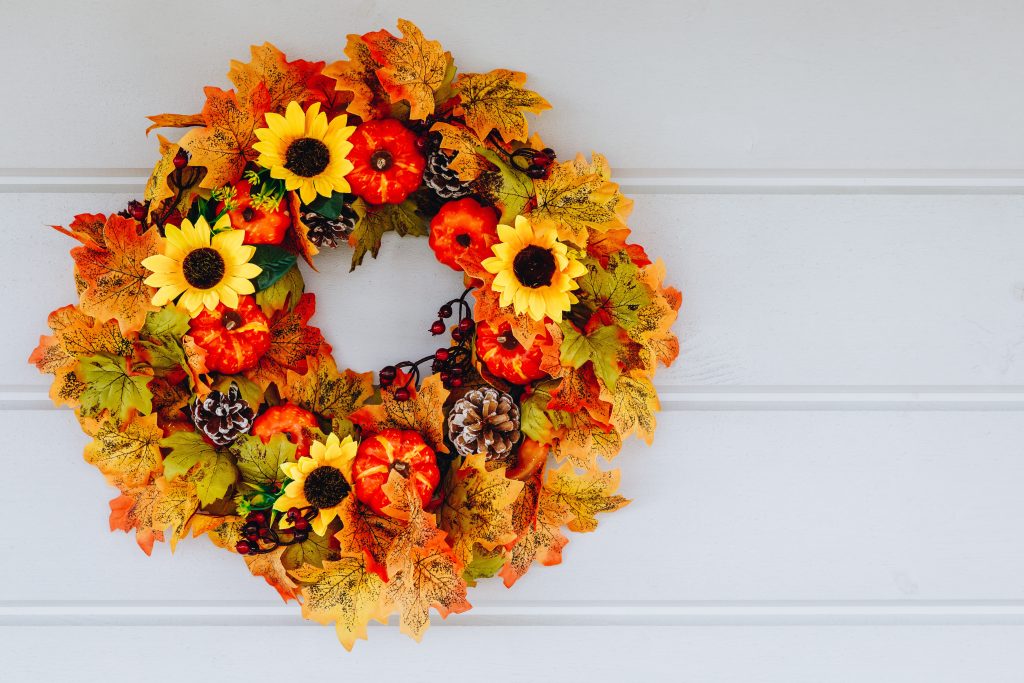 Autumn wreath with sunflowers, pumpkins and maple leaves on wooden door
