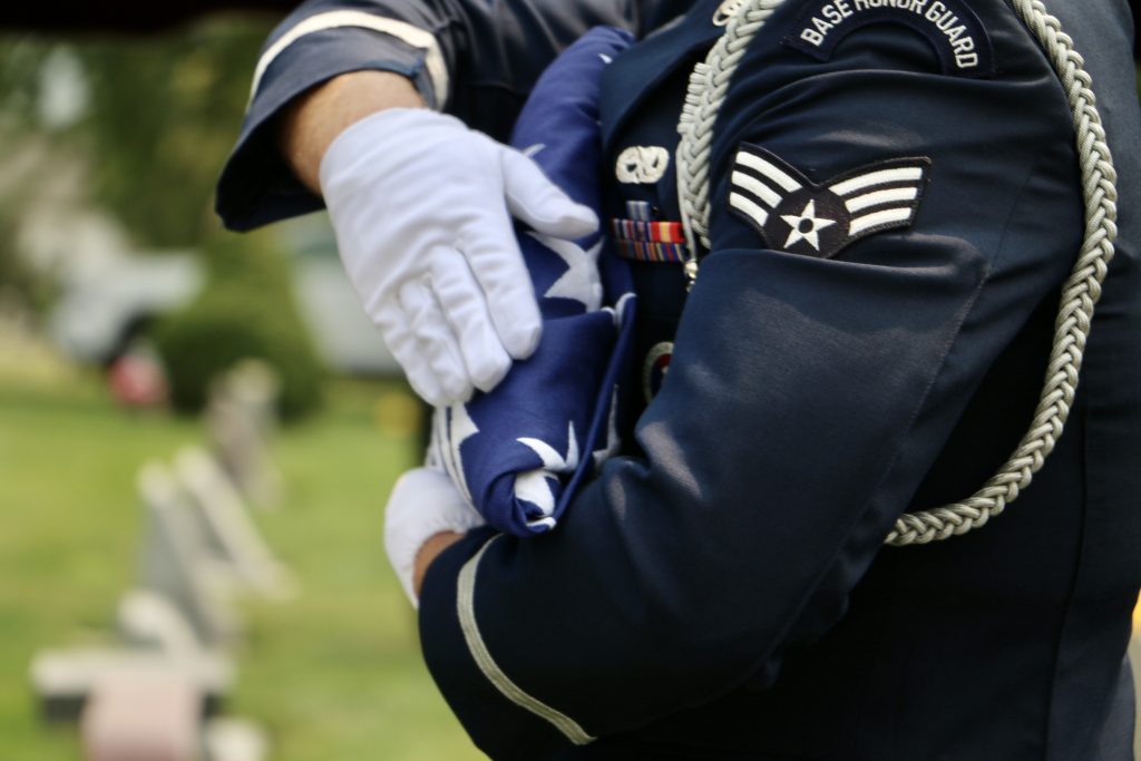 US Air Force Honor Guard body bearer inspects tricorn flag before presenting to lead body bearer.